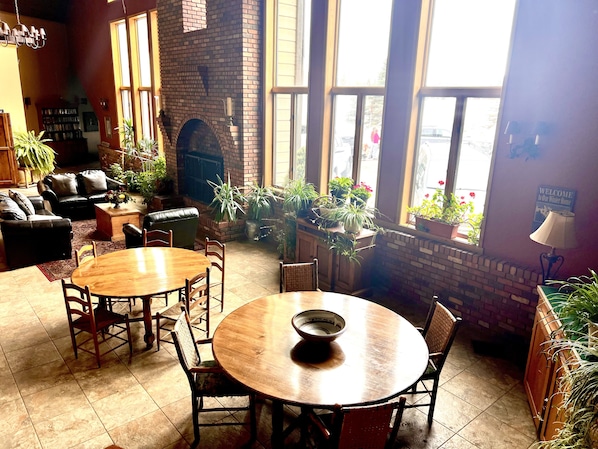 A cozy indoor space with a brick fireplace, comfortable seating, and a dining area.