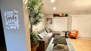 A modern living room with a grey sofa, a coffee table, and a potted plant. - Spacious and Private Vacation Rentals in Poway CA. (Poway)