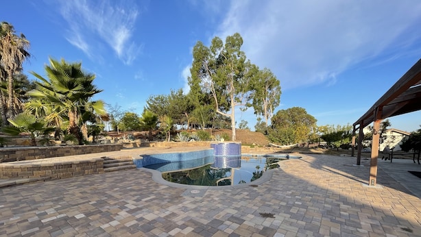 A swimming pool with a tiled edge, surrounded by a brick patio and palm trees. - Spacious and Private Vacation Rentals in Poway CA. (Poway)