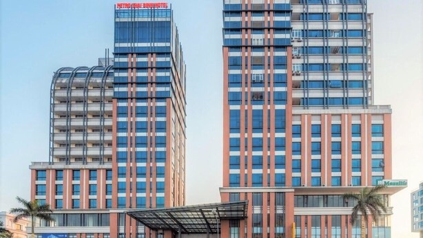 Un hotel moderno con una fachada de vidrio destacada, varios pisos y una estructura curva distintiva a la izquierda.