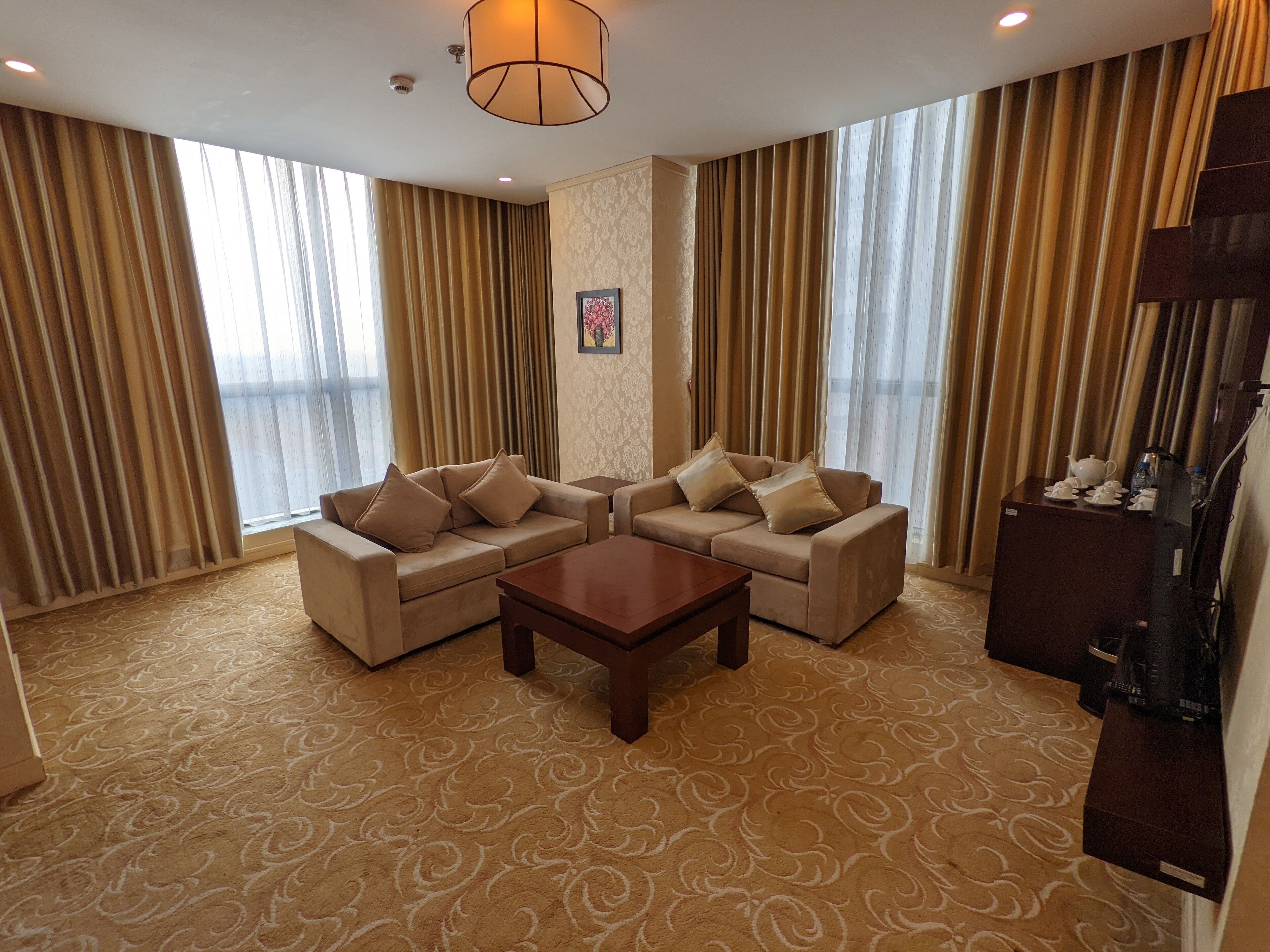 A hotel room with a sofa set, a coffee table, and a cabinet with a television.