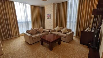 A hotel room with a sofa set, a coffee table, and a cabinet with a television.