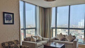 Amplia sala de estar con ventanas grandes, un conjunto de sofá, un sillón estampado y una mesa de centro.