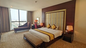 Habitación de hotel con una cama grande, un sofá, un escritorio y vistas a la ciudad.