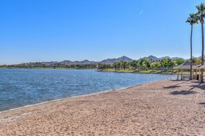 Escape to a serene lakeside haven with a wide sandy beach, tranquil lake, and majestic mountain backdrop.