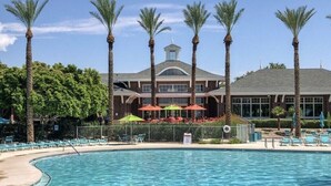 Un hotel con piscina, palme e area salotto all'aperto.