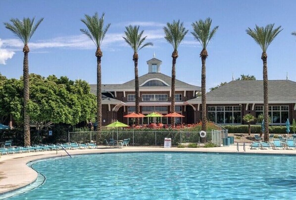 Relax by the pool surrounded by palm trees and lounge chairs.