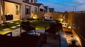 Relax in an outdoor space with a fire pit and comfortable seating surrounded by lush greenery.