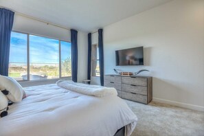 Relax in this serene bedroom with a large bed, dresser, and flat-screen TV.