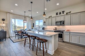Enjoy cooking in this well-lit kitchen with a large island and bar stools, featuring a stainless steel oven and microwave.