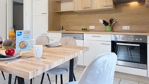A modern kitchen with wooden cabinets, a built-in oven, and a dining area with a table and chairs. - Cosy apartment in villa for 6 guests with WIFI, TV, terrace and pets allowed (Bad Wildungen)