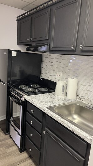 Microondas, cafetera y tetera, utensilios de cocina y toallas de papel 