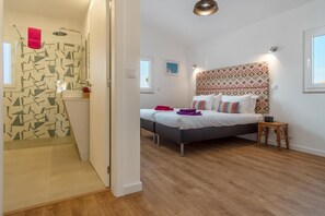 A room with a shower, two beds, a wooden floor, and a patterned headboard. - LV Premier LA2 heated pool, AC, garden, sea view (Sesimbra)
