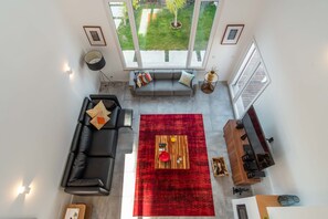 A modern living room with a black sofa, red rug, wooden coffee table, and a TV stand. - LV Premier LA2 heated pool, AC, garden, sea view (Sesimbra)