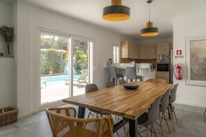 A modern kitchen with a wooden dining table, grey chairs, and pendant lighting. - LV Premier LA2 heated pool, AC, garden, sea view (Sesimbra)