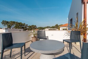 A rooftop terrace with a round table and four chairs, surrounded by potted plants. - LV Premier LA2 heated pool, AC, garden, sea view (Sesimbra)