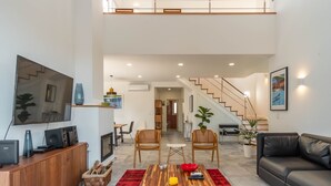Amplia sala de estar con techo alto, una escalera y un diseño moderno.