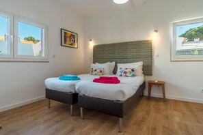 A double bed with a striped headboard, two bedside tables, and a small nightstand. - LV Premier LA2 heated pool, AC, garden, sea view (Sesimbra)
