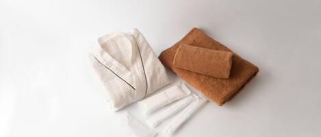 A neatly arranged set of towels and a folded robe on a white surface.