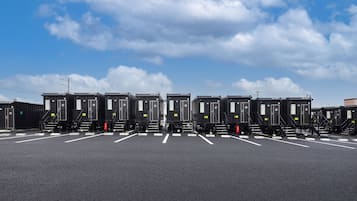 A parking lot with rows of black portable toilets labeled 01 to 10, under a partly cloudy sky.