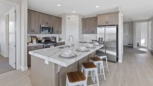 Una cocina moderna con una isla central, electrodomésticos de acero inoxidable y armarios de madera.