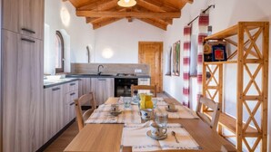 A cozy kitchen with wooden cabinets, a dining table set with cups and a yellow pitcher, and a wooden ceiling. - La Quercia by Interhome (Mondovì)