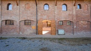 Um edifício de tijolos com várias janelas em arco e uma porta central.