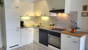 Une cuisine moderne avec des armoires blanches, une hotte noire, un lave-vaisselle et un plan de travail en bois.