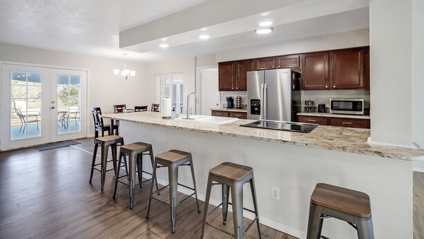 A modern kitchen with a large island, stainless steel appliances, and wooden bar stools. - Game Room - Mountain Views - King Bed - near Golf Course - Intel - Rust Medical  (Albuquerque)
