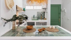 Une cuisine moderne avec une porte verte, un luminaire suspendu en fibres tressées et un revêtement mural carrelé.