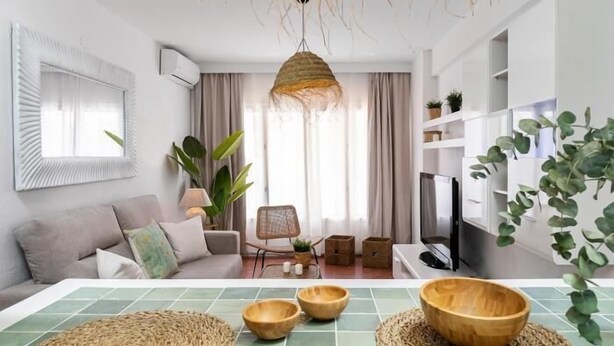 Un salon moderne avec un canapé, une table à manger ornée de bols en bois, un luminaire suspendu et un téléviseur.