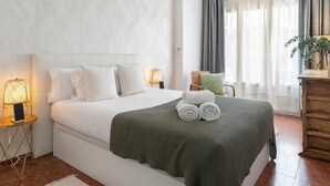 Une chambre moderne avec un grand lit, une commode en bois et un luminaire suspendu.