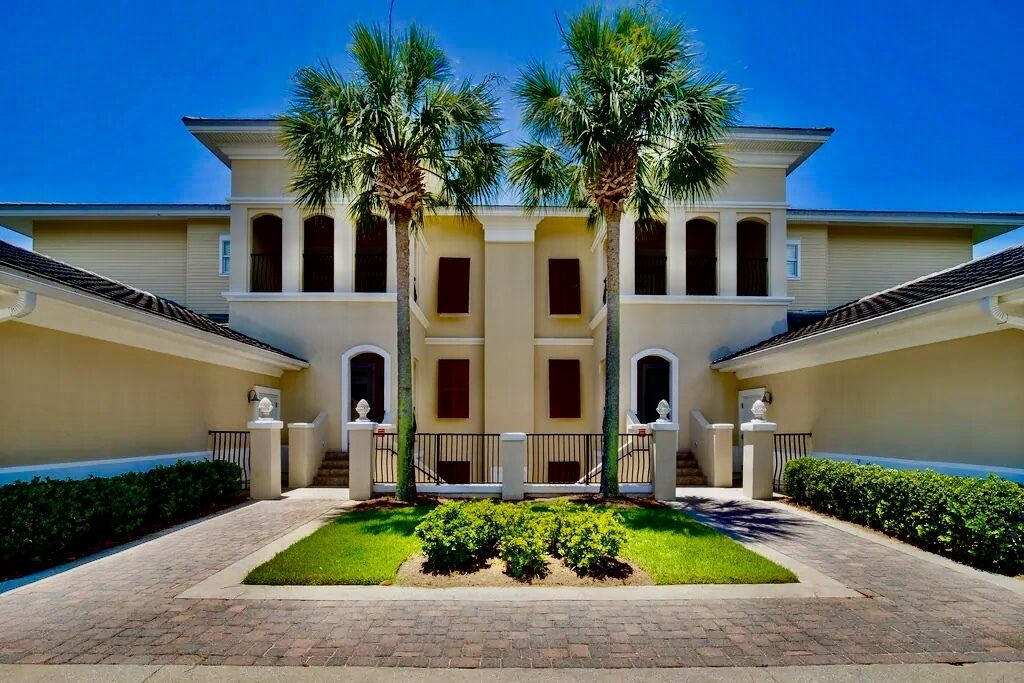 A symmetrical building with a central courtyard, palm trees, and a brick pathway.
