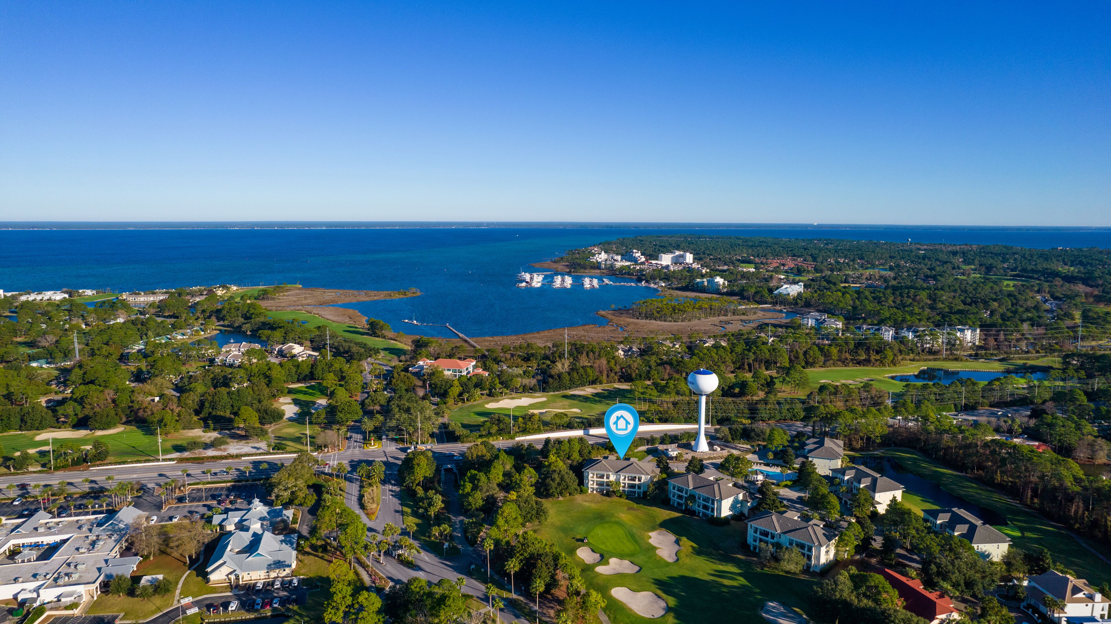 Vista aérea de una zona costera con un campo de golf, edificios residenciales y un puerto deportivo.