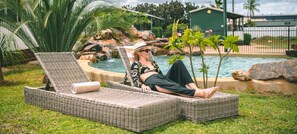 Una piscina al aire libre, sombrillas, sillones reclinables de piscina