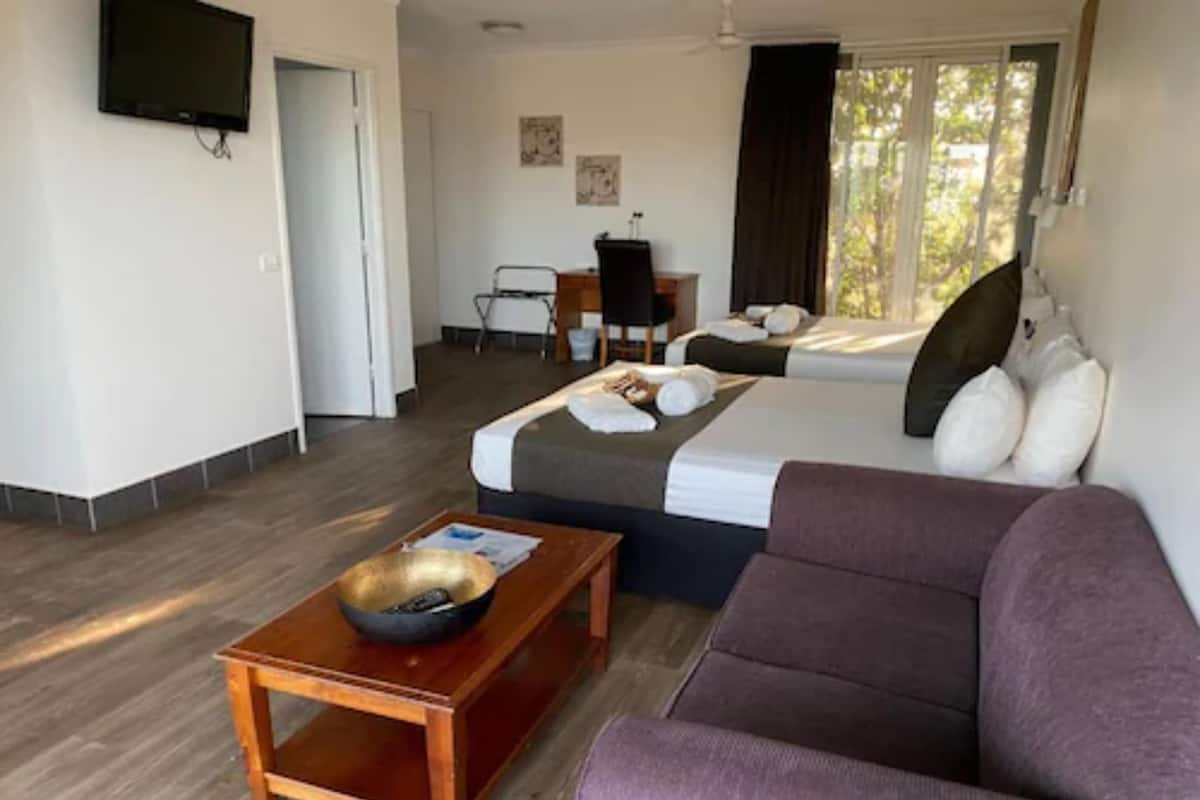 A hotel room with a bed, a sofa, a desk, a chair, and a television.