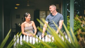 A couple standing in a garden with a white picket fence and greenery. - Darwin Resort (Winnellie)