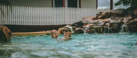 Una piscina al aire libre, sombrillas, sillones reclinables de piscina