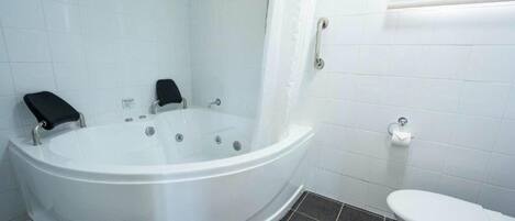 A bathroom with a white bathtub, a toilet, and a shower curtain.