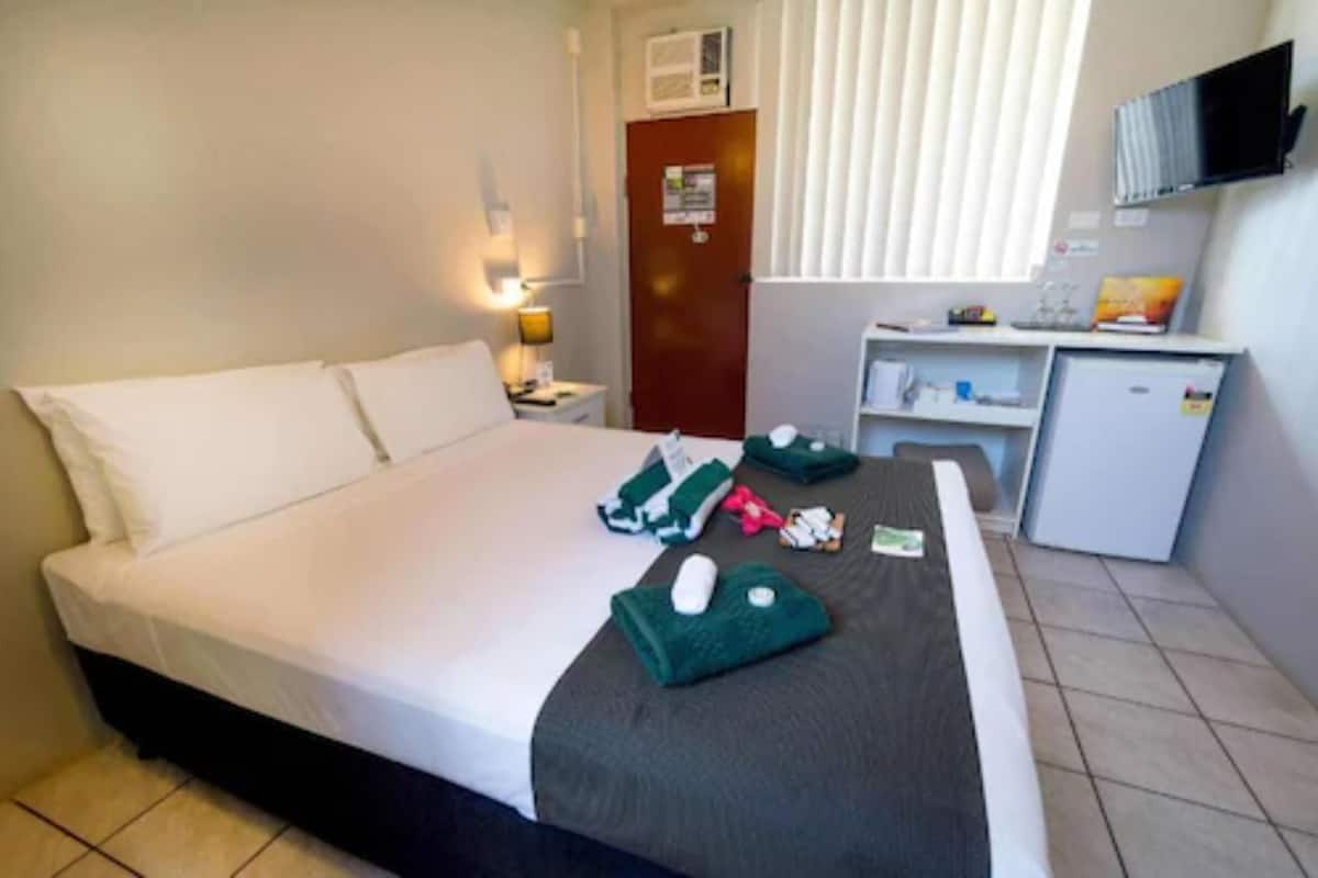 A hotel room with a bed, a desk, a TV, and a small refrigerator.