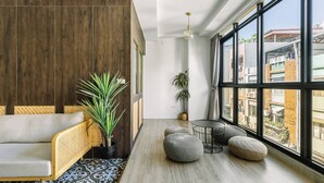 A modern living room with a sofa, ottomans, a small table, and large windows offering a view of the city. - Nan Nan (Kaohsiung)