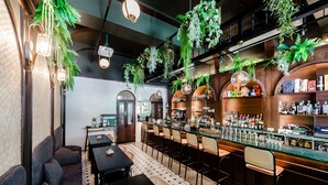 A bar area with seating, hanging plants, and shelves of bottles. - Nan Nan (Kaohsiung)