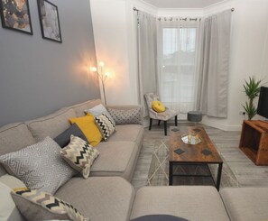 A living room with a sofa, armchairs, a coffee table, and a TV stand.