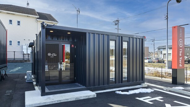 A modern hotel with a glass entrance, a parking lot, and a clear sky. - HOTEL R9 The Yard Inabe (Inabe)