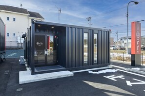 Un hôtel moderne avec une entrée en verre, un parking et un ciel dégagé.