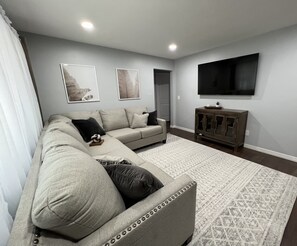 Relax in this stylish living room with a sectional sofa, decorative pillow, and flat-screen TV.