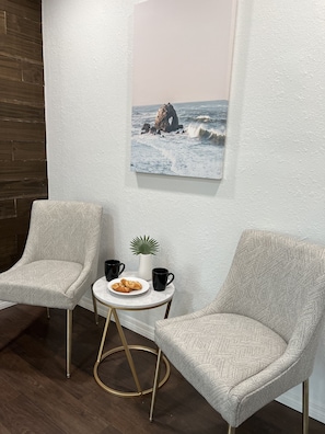 Relax in this inviting seating area with two comfortable chairs and a small table, featuring a beautiful coastal view.