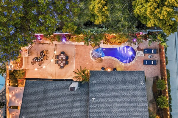 An aerial view of a rooftop with a swimming pool, outdoor seating, and surrounding greenery. - Charming Coastal Escape: Resort-Style Walk-In Spa (Oceanside)