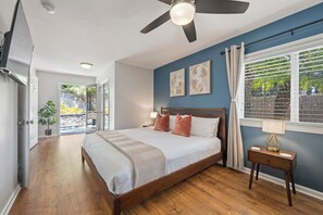 A bedroom with a bed, ceiling fan, bedside table, and a window with curtains.