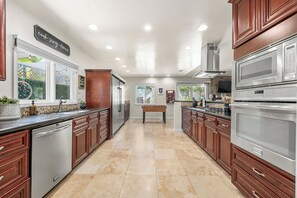 A kitchen with wooden cabinets, stainless steel appliances, and a foosball table.